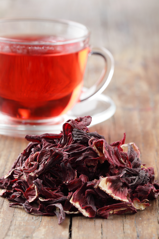 Brewed hibiscus tea beside dried hibiscus flowers